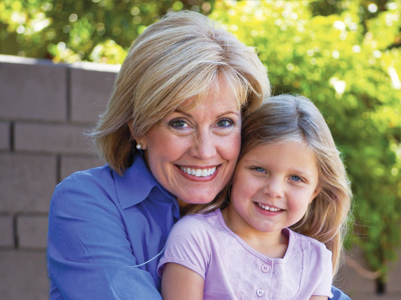 Grandmother holding her grandaughter and smiles.