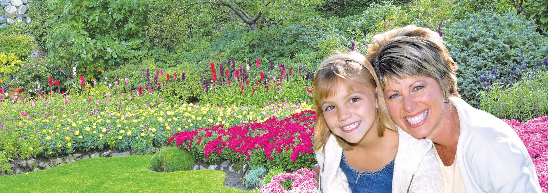 Mother and daughter smiling in a garden.