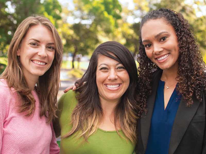 Three lady friends smiling outside.